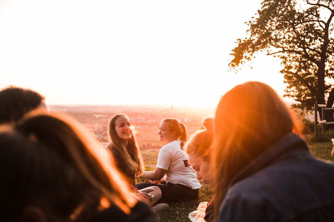 Friends sitting together on a hillside at golden hour, talking and laughing